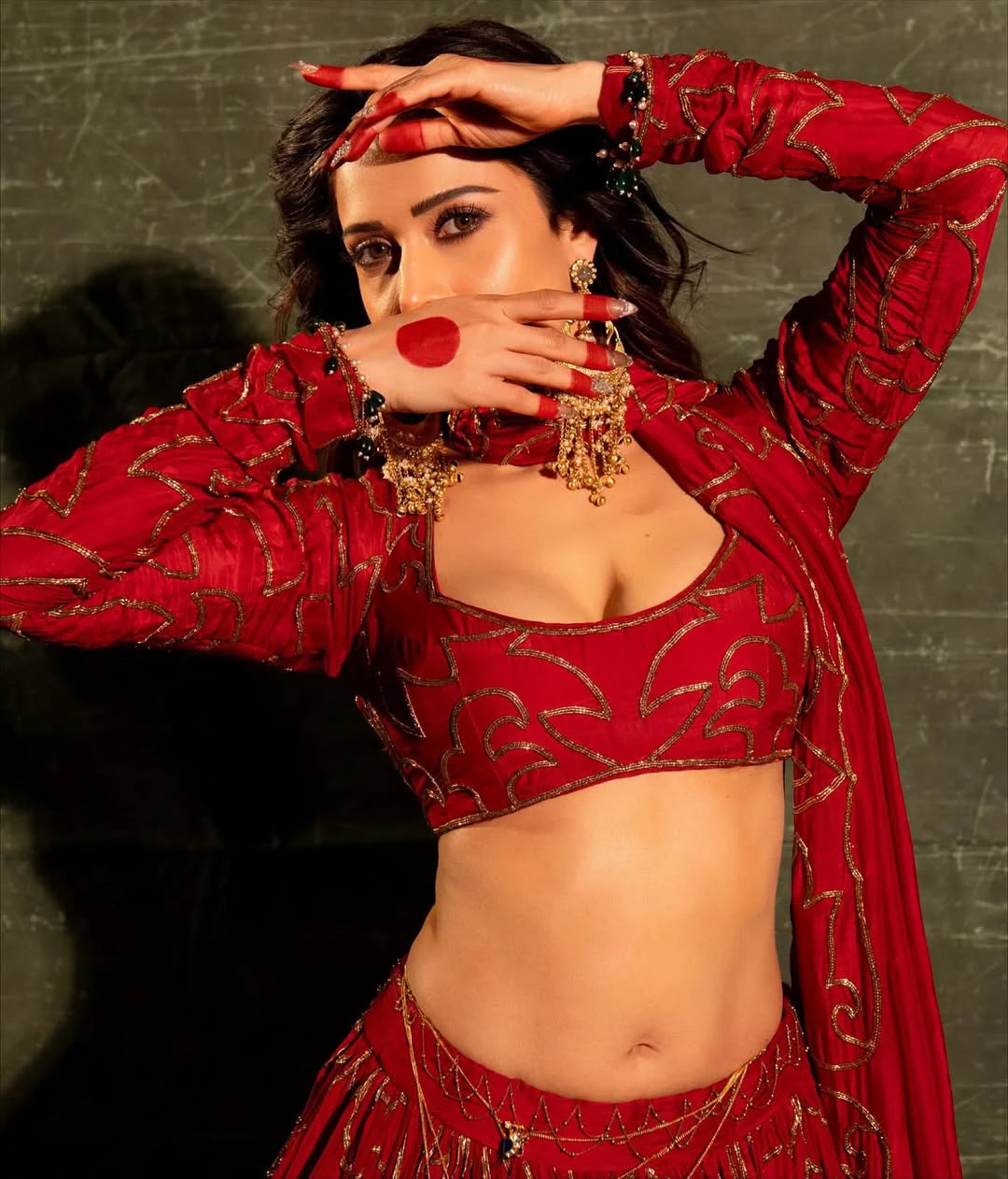 Stylish woman wearing red festive outfit with heavy earrings and layered accessories
