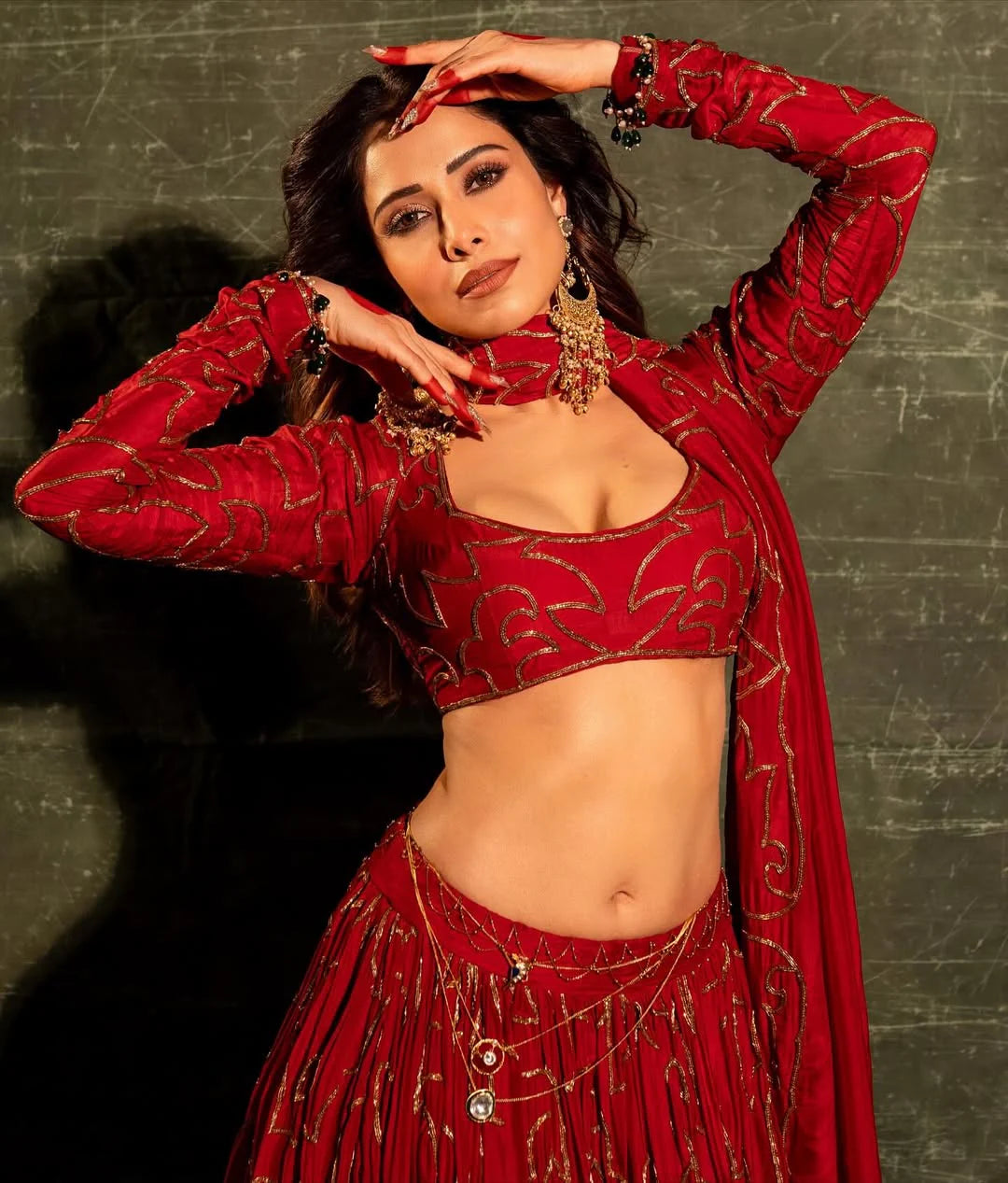 Bridal-inspired red lehenga look with gold embroidery and statement jewelry styling

