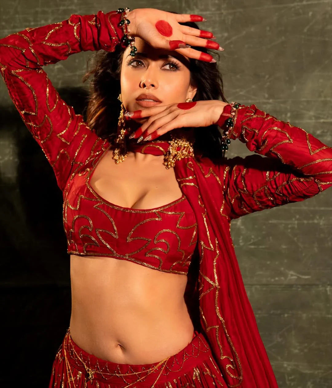 High fashion portrait of model in red lehenga with ornate gold embellishments
