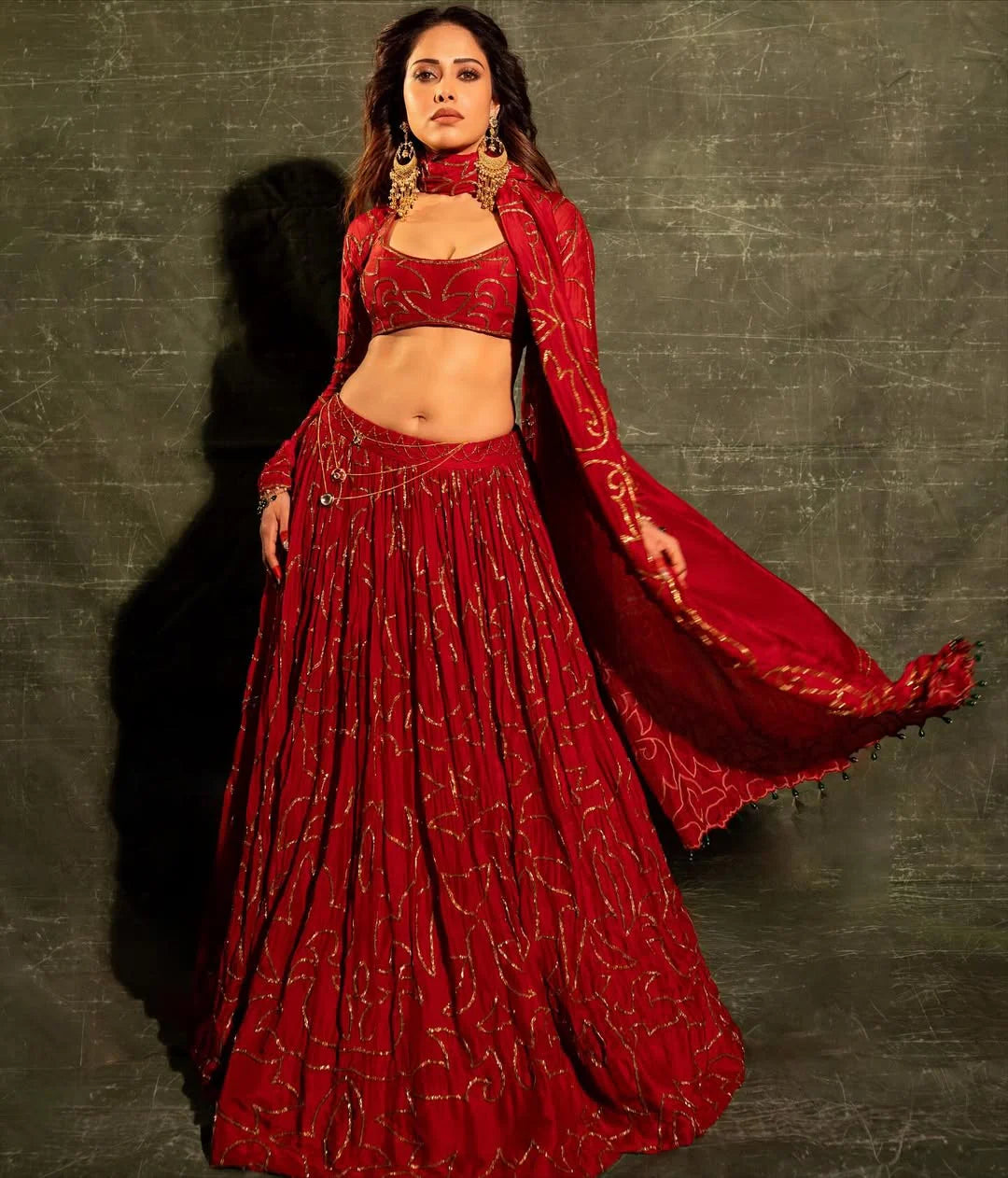 Elegant ethnic wear featuring red lehenga choli with intricate gold patterns and jewelry
