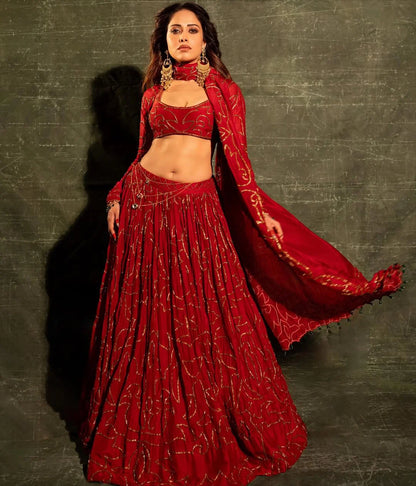 Elegant ethnic wear featuring red lehenga choli with intricate gold patterns and jewelry
