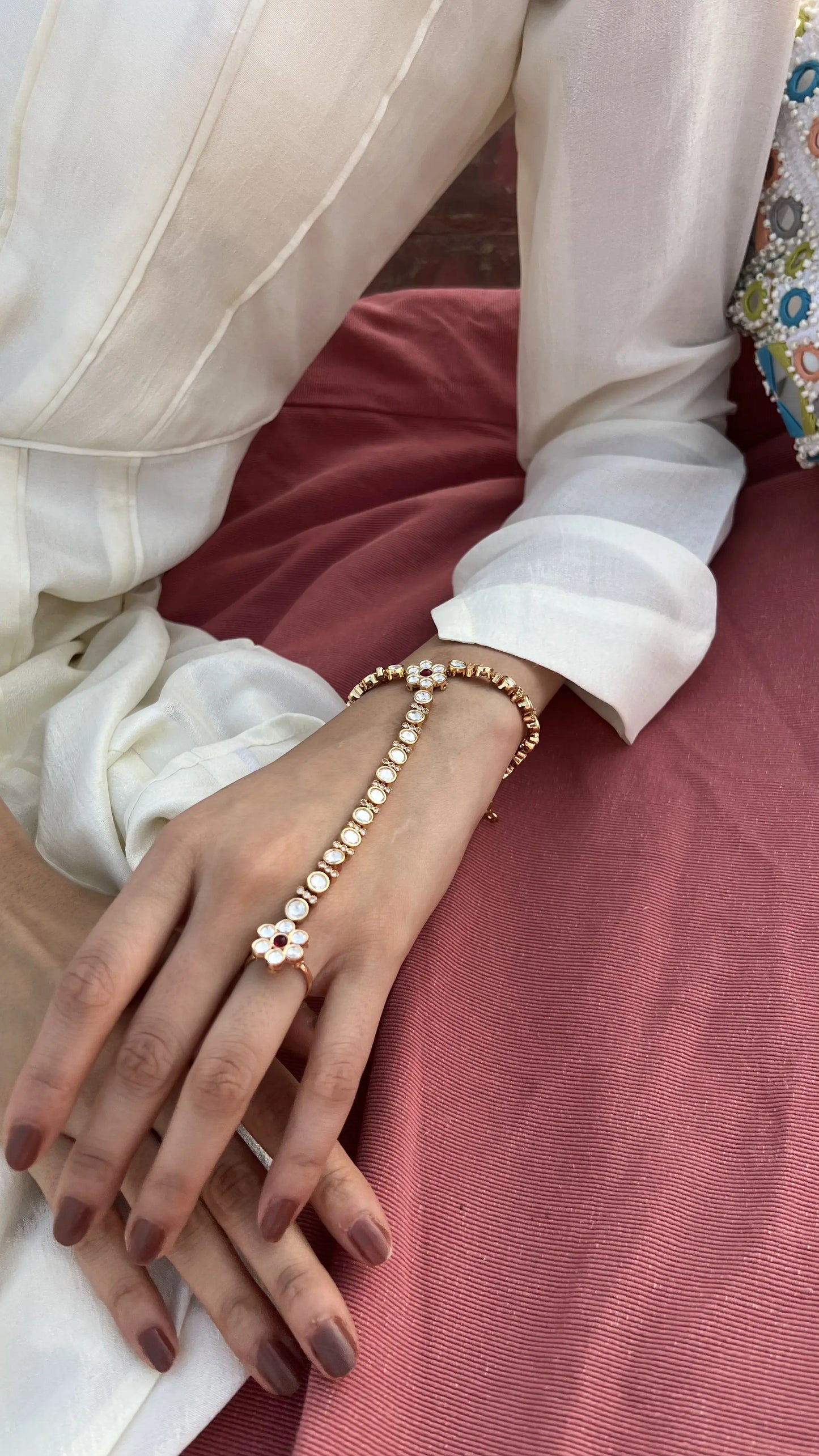 Lifestyle image of a woman in a white ensemble adorned with coordinated green gemstone earrings and necklace, set against a calm riverside backdrop.
