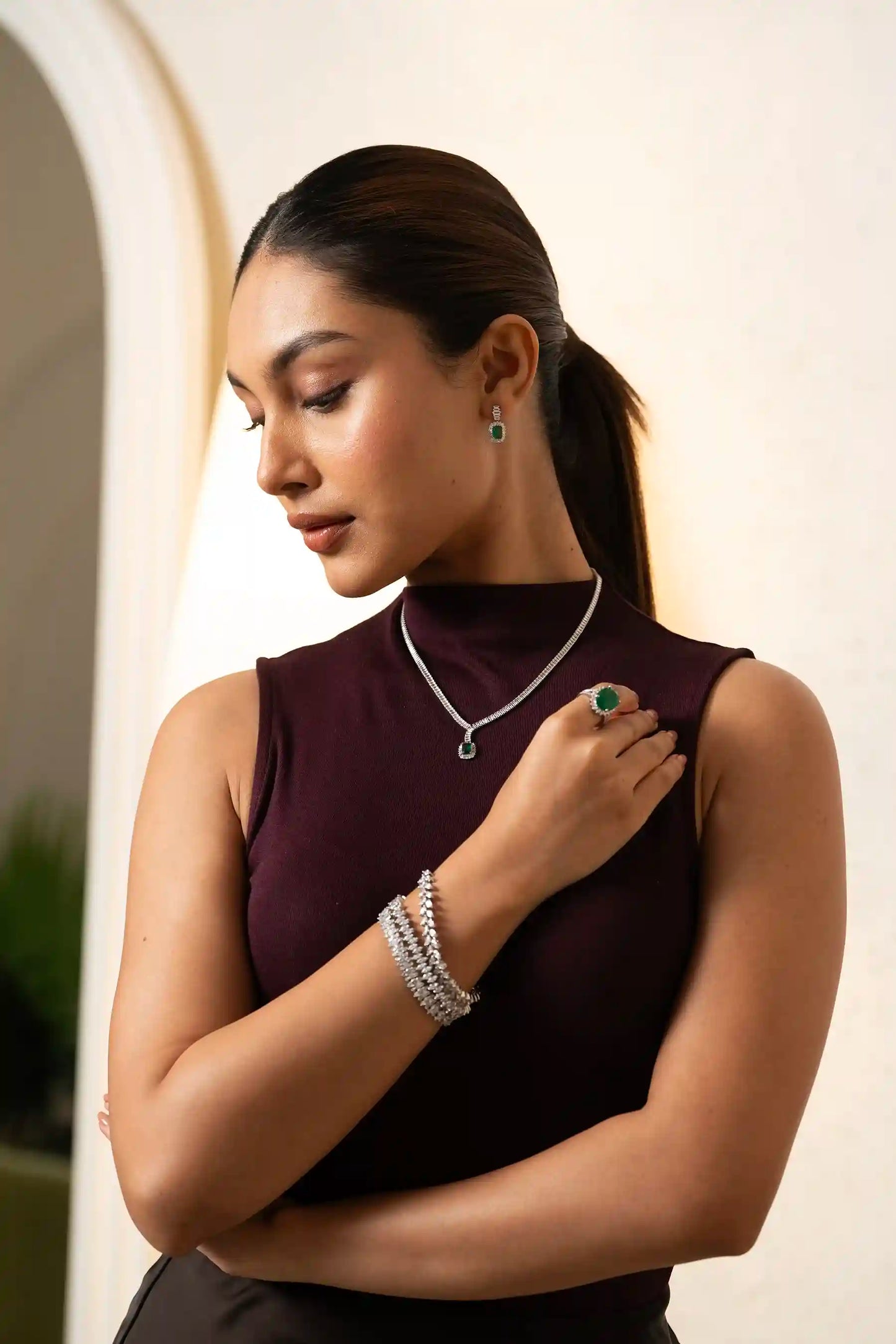 Close-up of diamond bracelet and emerald ring on hand, showcasing fine jewelry craftsmanship and luxury design