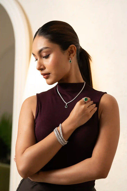 Close-up of diamond bracelet and emerald ring on hand, showcasing fine jewelry craftsmanship and luxury design