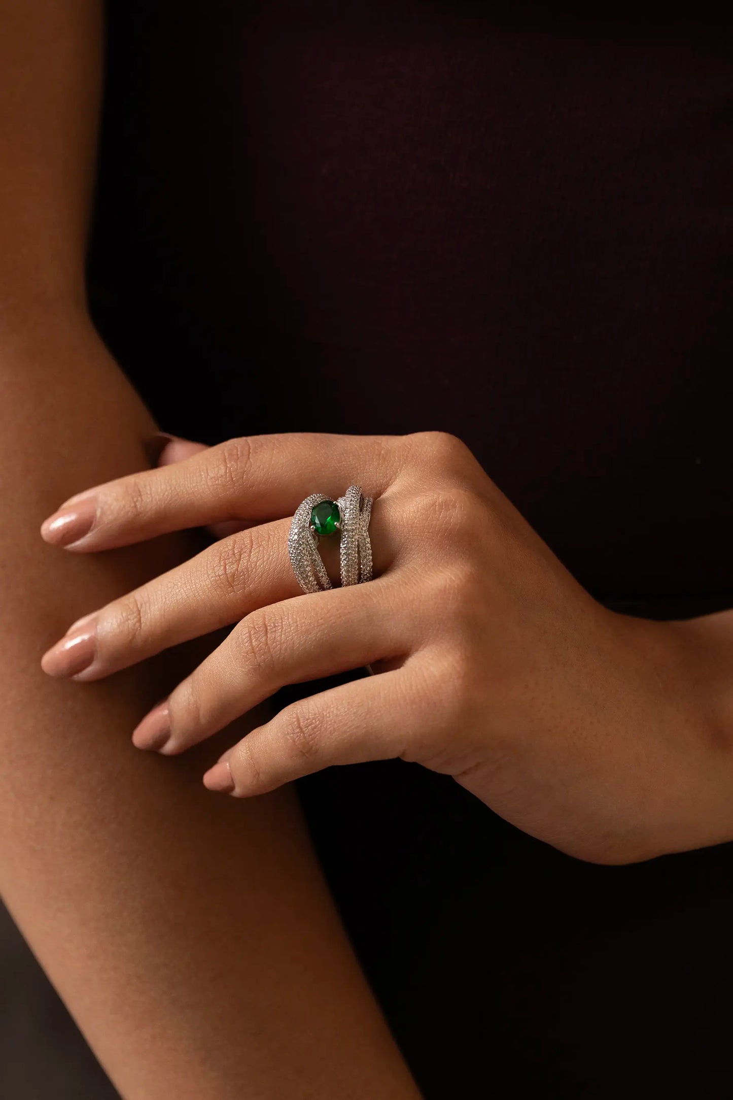 Macro close-up of oval emerald ring with diamond pavé split bands, high-end fine jewelry detail