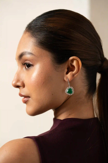 Close-up detail of a fine jewelry emerald drop earring with heart-shaped center stone and diamond accents.