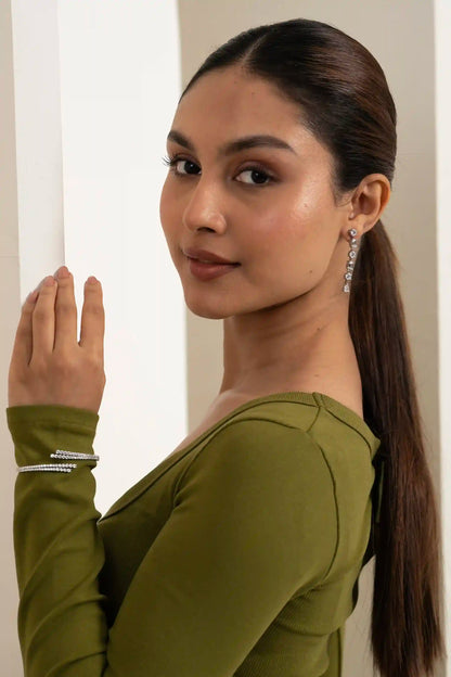 Close-up portrait of a woman with sleek ponytail wearing diamond drop earrings and stacked bracelets, stylish jewelry look