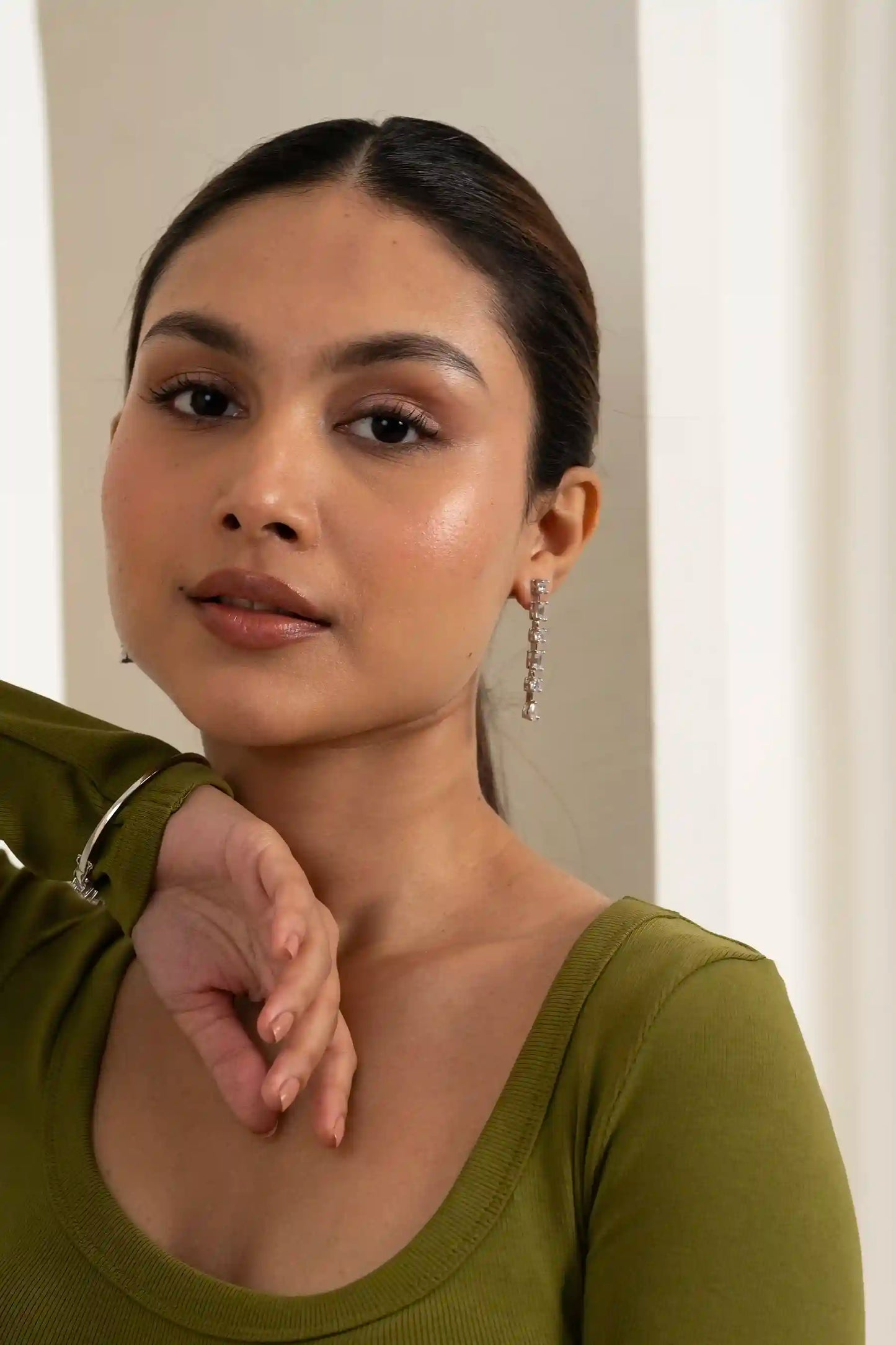 Woman posing with sleek ponytail and sparkling drop earrings, highlighting contemporary fashion jewelry design