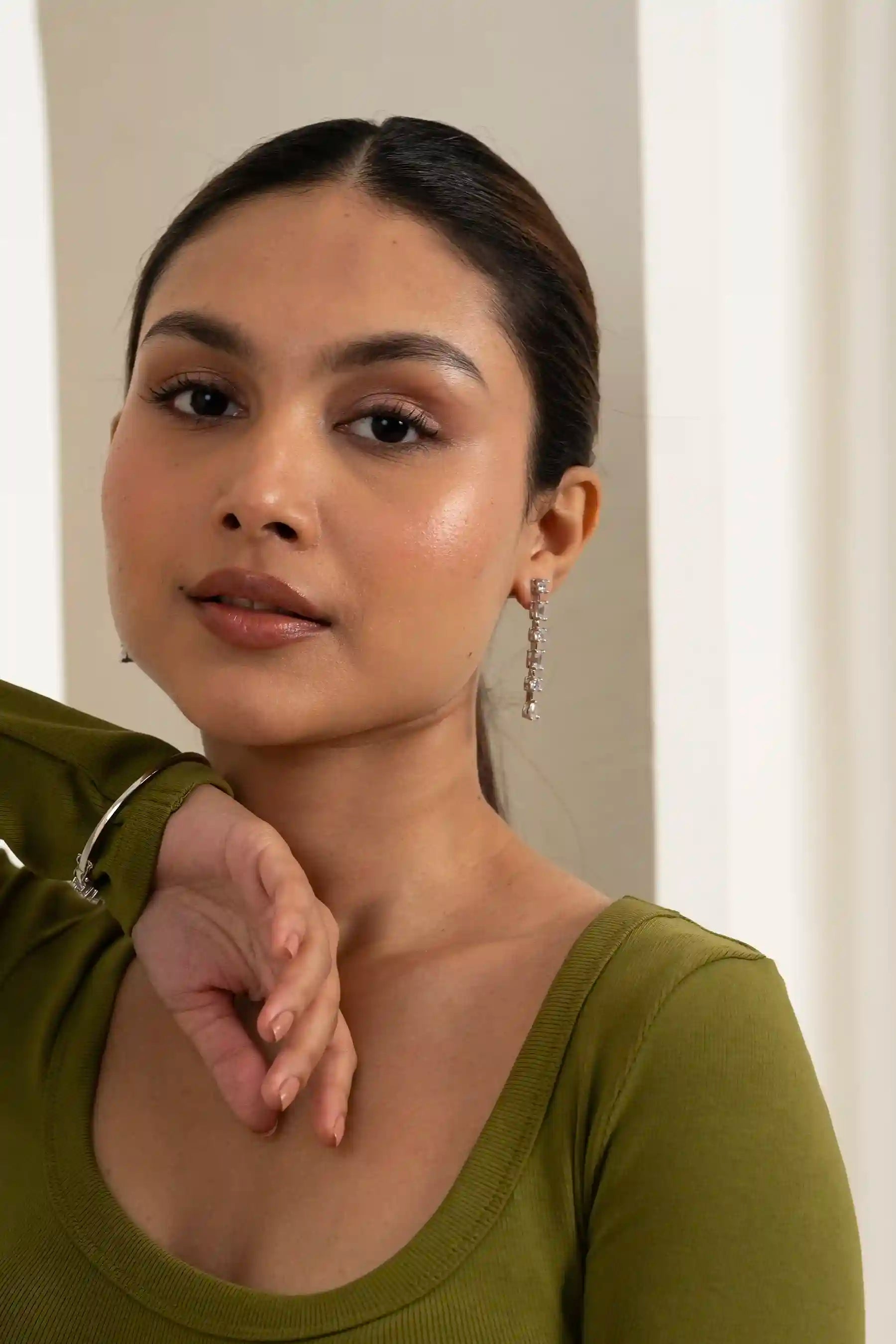 Woman posing with sleek ponytail and sparkling drop earrings, highlighting contemporary fashion jewelry design