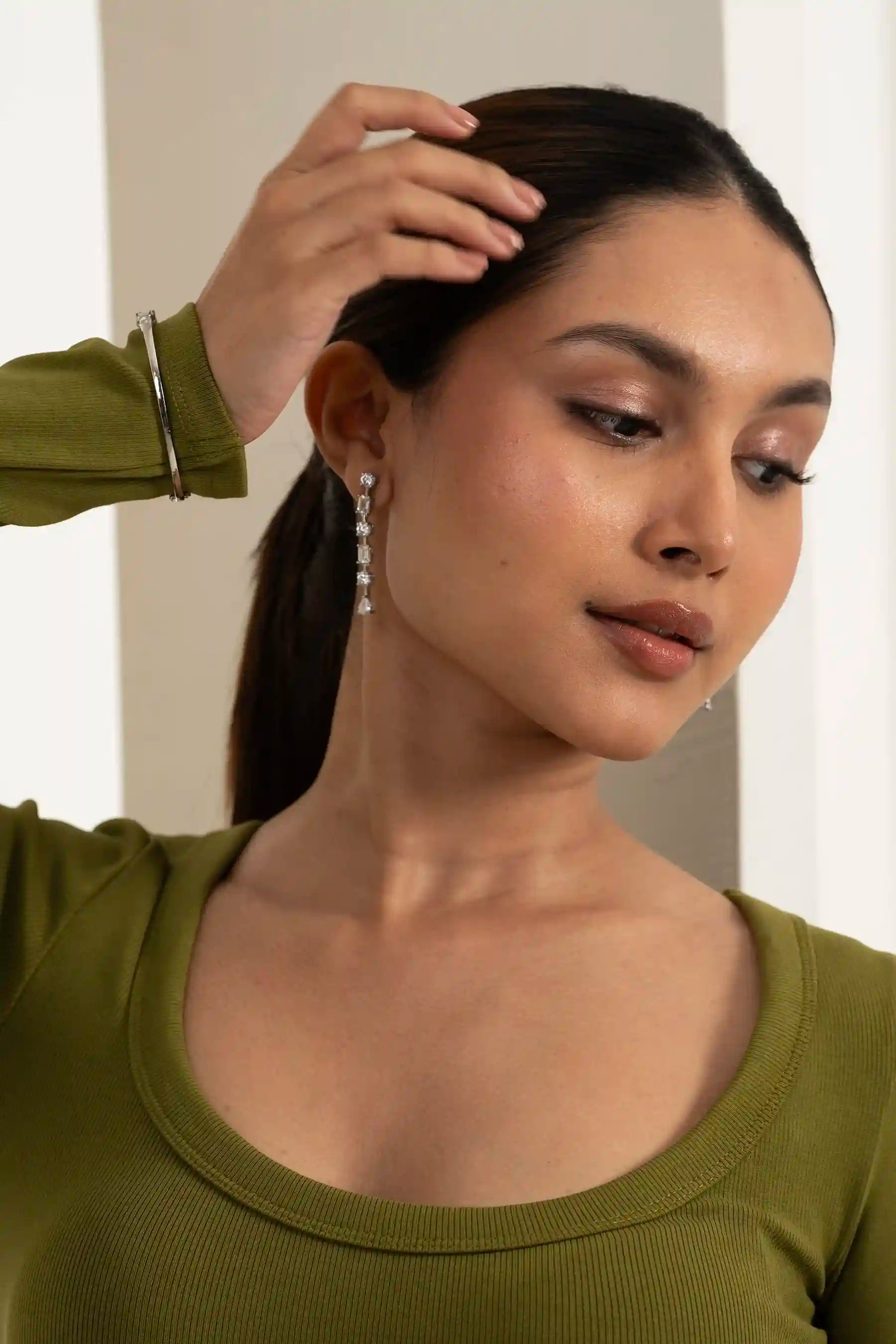 Stylish woman with long hair wearing shimmering drop earrings, emphasizing trendy fashion jewelry aesthetics