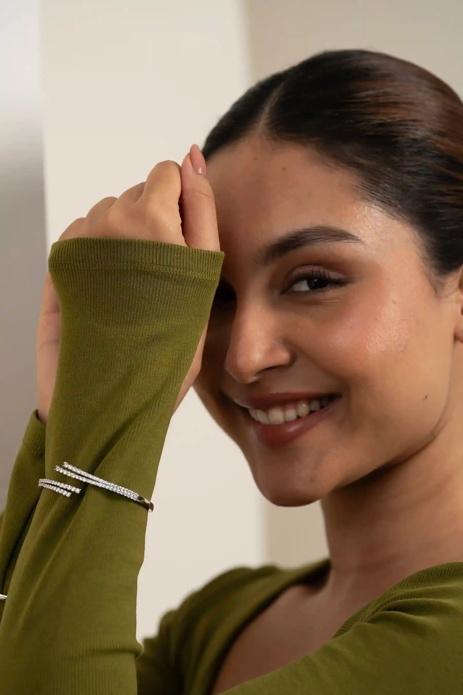 Stylish female model in green outfit wearing diamond earrings and sleek bracelets, highlighting elegant jewelry design