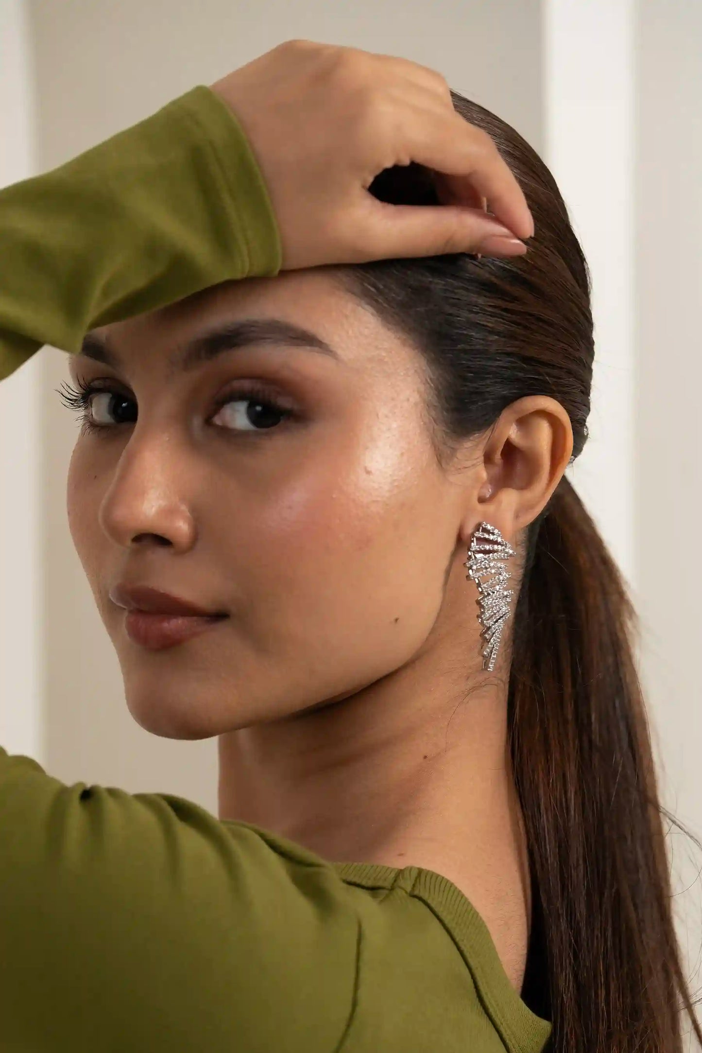 Close-up of a woman wearing a diamond feather ear sweep earring, minimal premium styling, soft editorial lighting
