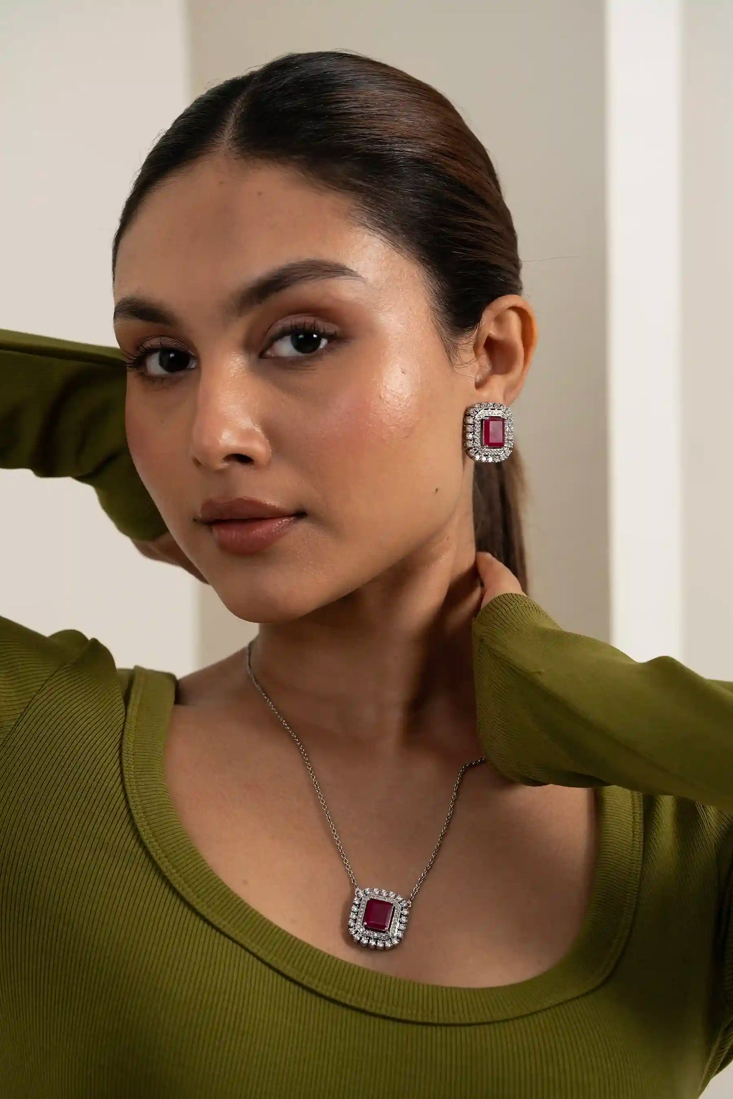 Cushion-cut ruby necklace set with diamond halo earrings styled for occasion wear with natural candid expression