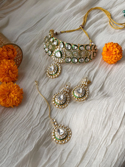Traditional gold and kundan choker necklace with green stones in soft natural lighting
