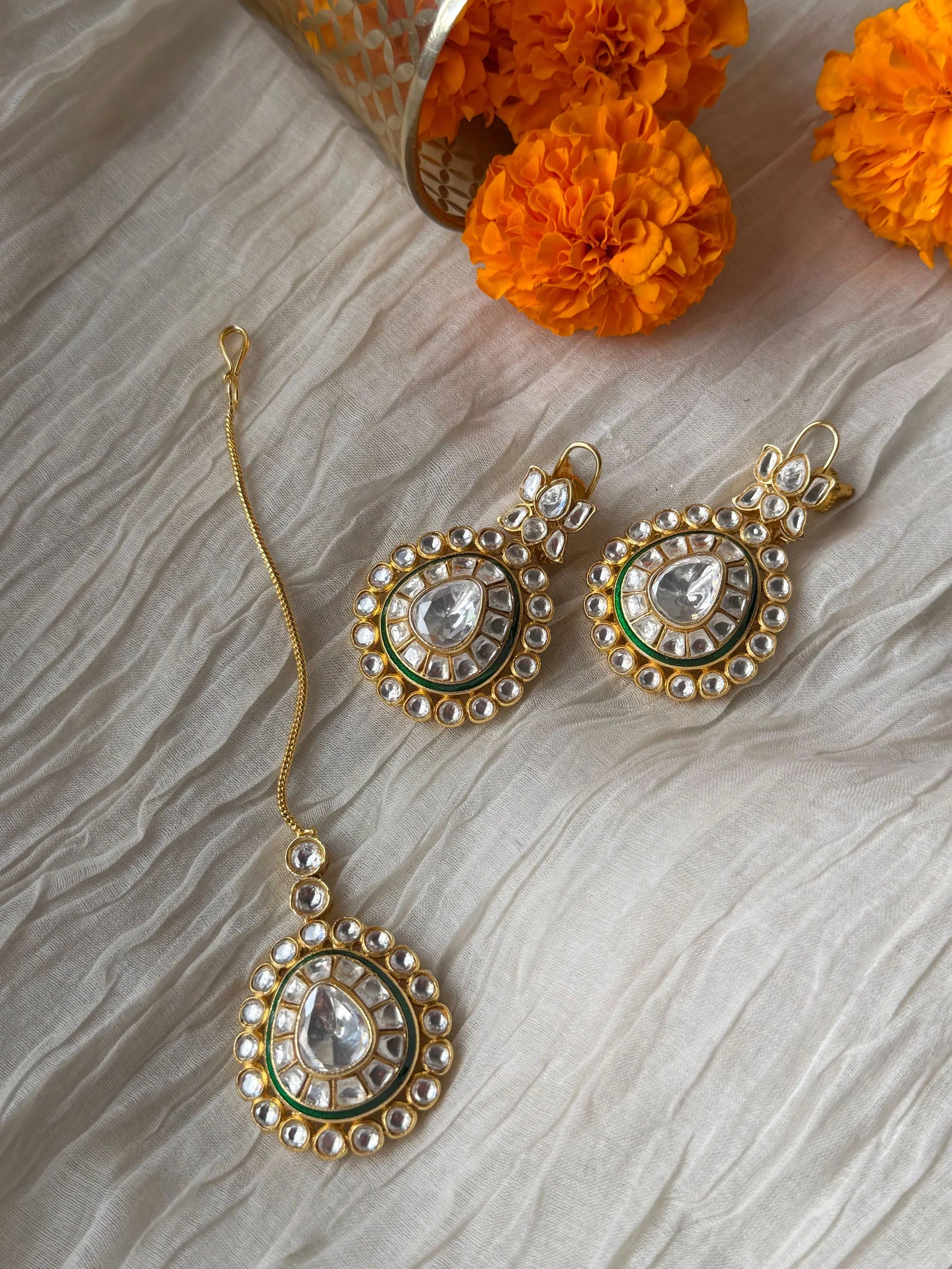 Indian bridal choker necklace with green and white stones displayed on soft fabric background
