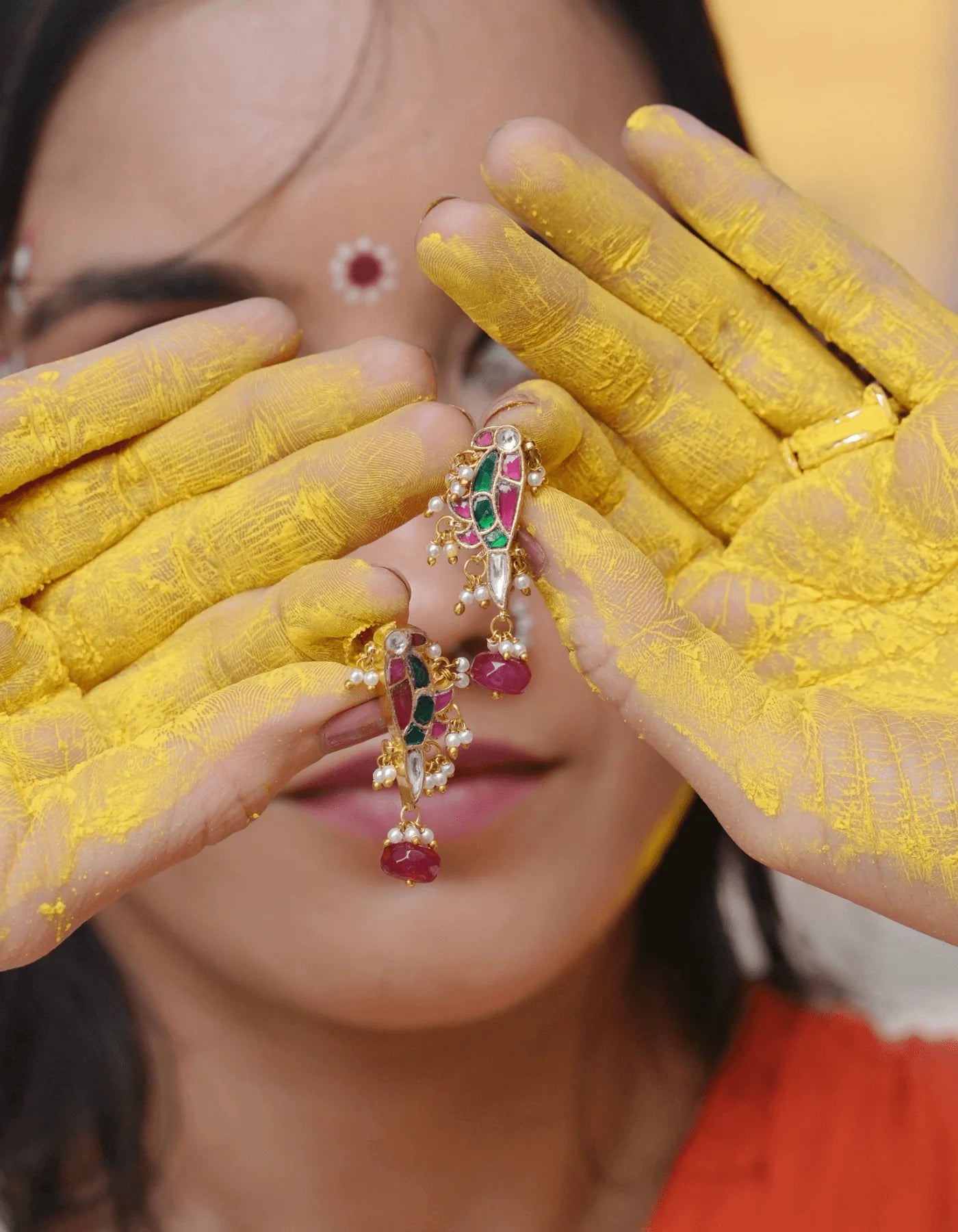 Refined portrait of a woman showcasing understated earrings and a classic bindi, styled in a warm, floral setting.
