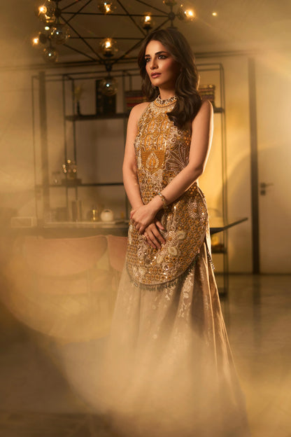 Close-up of a woman in a richly embroidered golden outfit with statement jewelry and soft lighting

